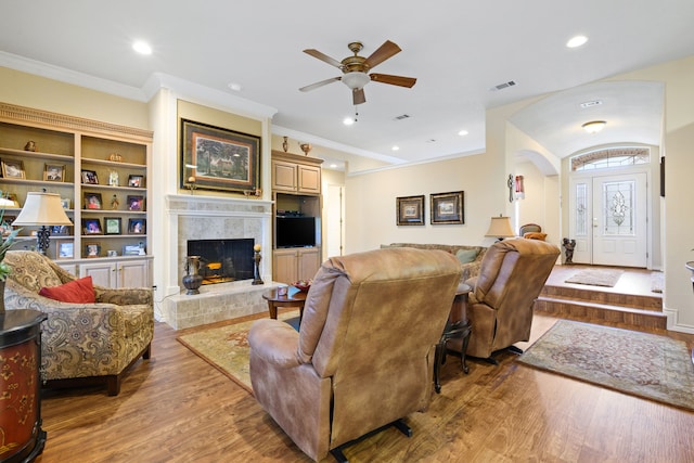 living room with ornamental molding, wood finished floors, recessed lighting, and a premium fireplace