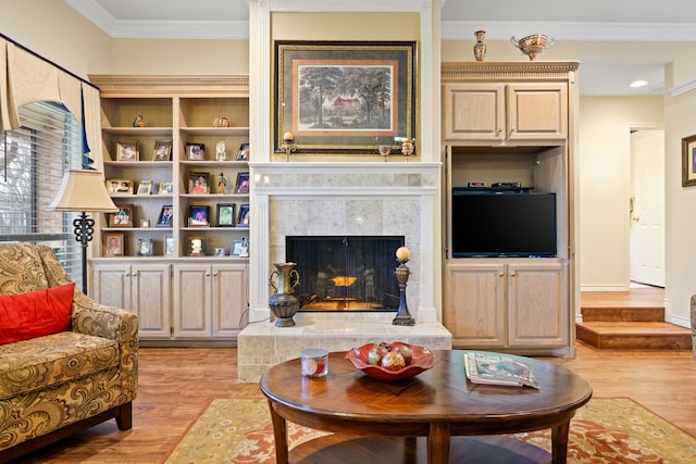 living area with baseboards, a tile fireplace, crown molding, and light wood finished floors