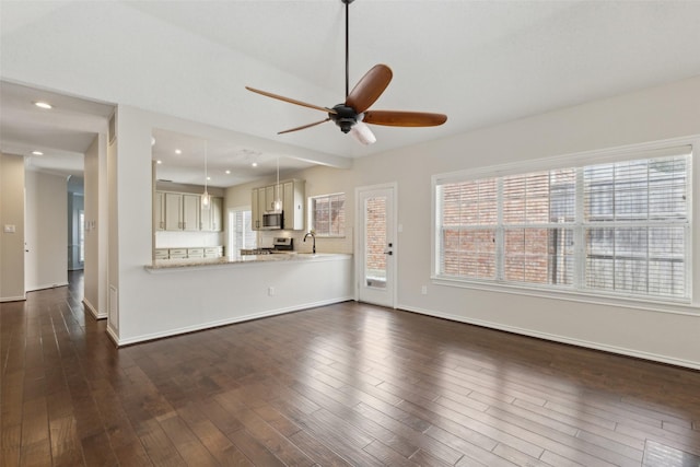 unfurnished living room featuring a sink, baseboards, ceiling fan, and dark wood-style flooring