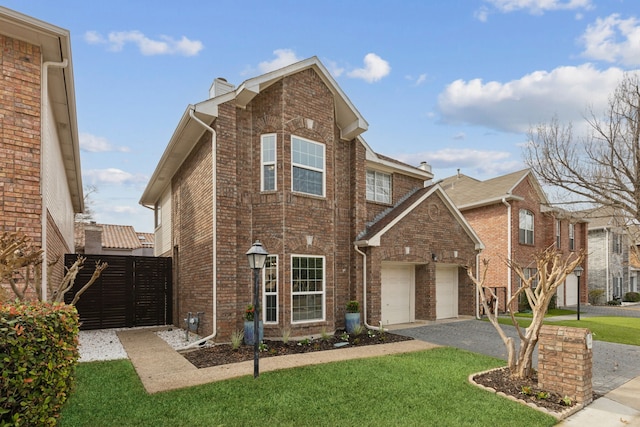 traditional home featuring a front lawn, brick siding, driveway, and a gate