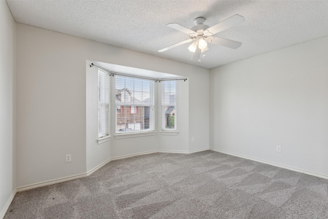 empty room featuring baseboards, a ceiling fan, carpet flooring, and a textured ceiling