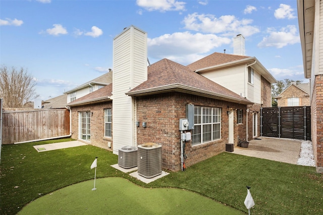 back of property with brick siding, a chimney, and a lawn