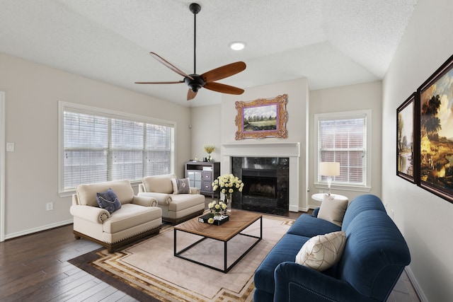 living room featuring a ceiling fan, hardwood / wood-style flooring, a textured ceiling, a high end fireplace, and baseboards