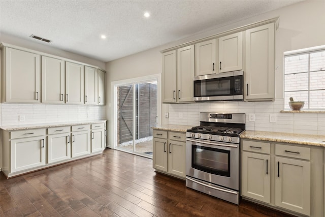 kitchen with visible vents, dark wood finished floors, appliances with stainless steel finishes, a textured ceiling, and tasteful backsplash