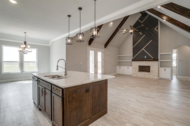 kitchen with baseboards, open floor plan, beam ceiling, a fireplace, and a sink