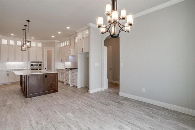 kitchen with backsplash, glass insert cabinets, premium range hood, light countertops, and arched walkways