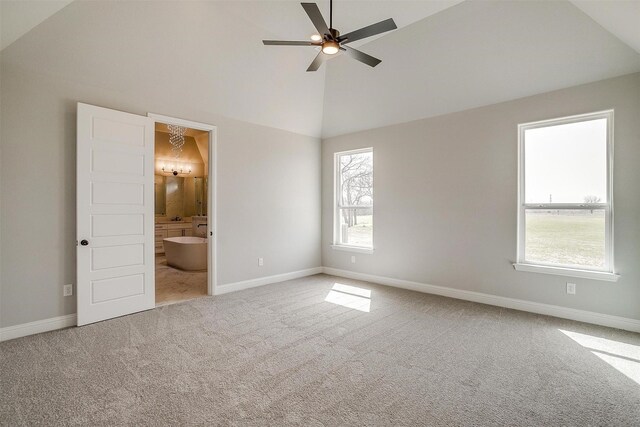 unfurnished bedroom with carpet flooring, baseboards, ensuite bathroom, and high vaulted ceiling