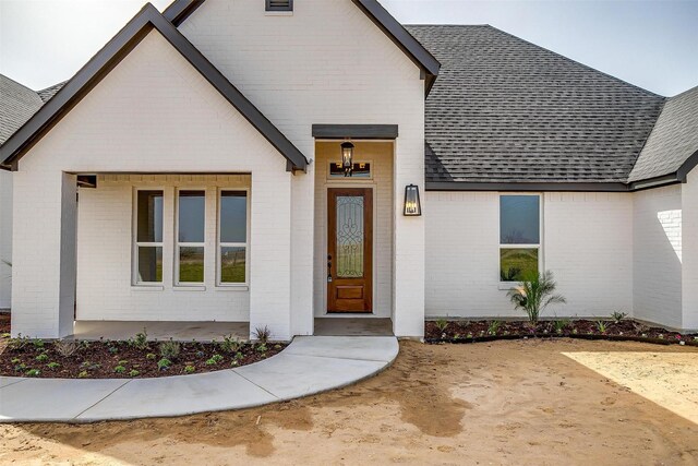 property entrance with brick siding and roof with shingles