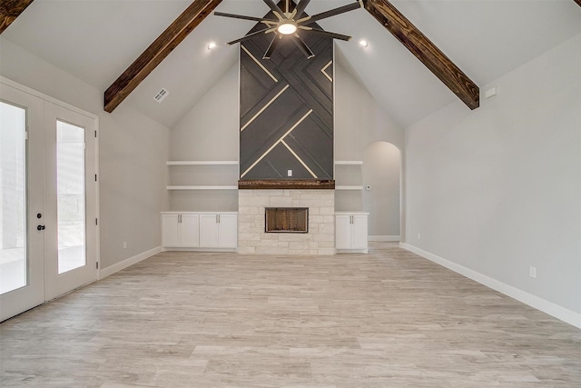 unfurnished living room featuring visible vents, baseboards, beam ceiling, a stone fireplace, and french doors