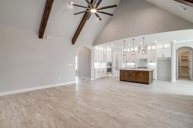 unfurnished living room featuring visible vents, baseboards, light wood-style floors, arched walkways, and high vaulted ceiling