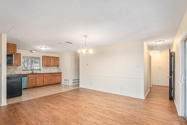 kitchen with tasteful backsplash, dishwasher, light wood-type flooring, brown cabinetry, and a sink