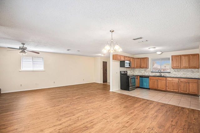 kitchen featuring open floor plan, stainless steel appliances, light wood-type flooring, and a sink