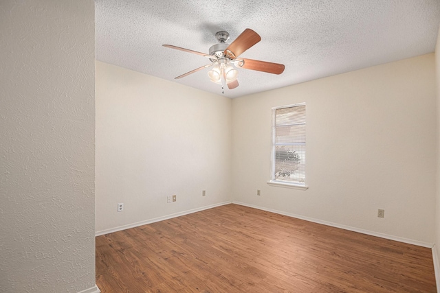 unfurnished room with a textured ceiling, wood finished floors, baseboards, and ceiling fan