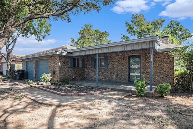 ranch-style home with a garage, brick siding, a chimney, and driveway