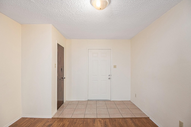 empty room featuring light wood-style flooring, a textured ceiling, and baseboards