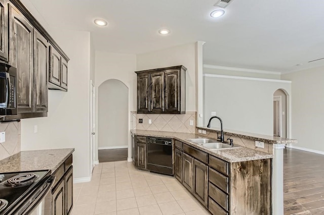 kitchen featuring light stone countertops, arched walkways, a sink, dark brown cabinetry, and black dishwasher