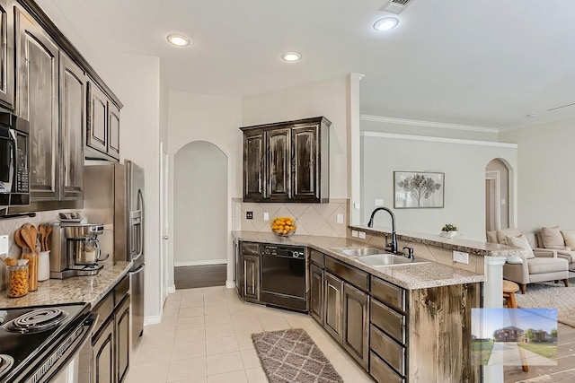 kitchen featuring backsplash, a breakfast bar, arched walkways, black appliances, and a sink