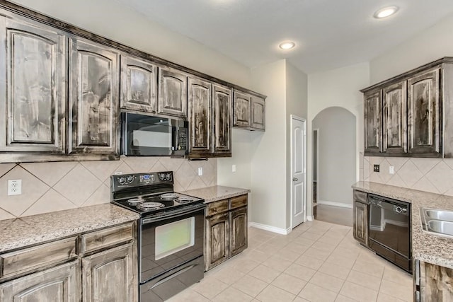 kitchen featuring tasteful backsplash, baseboards, dark brown cabinetry, arched walkways, and black appliances