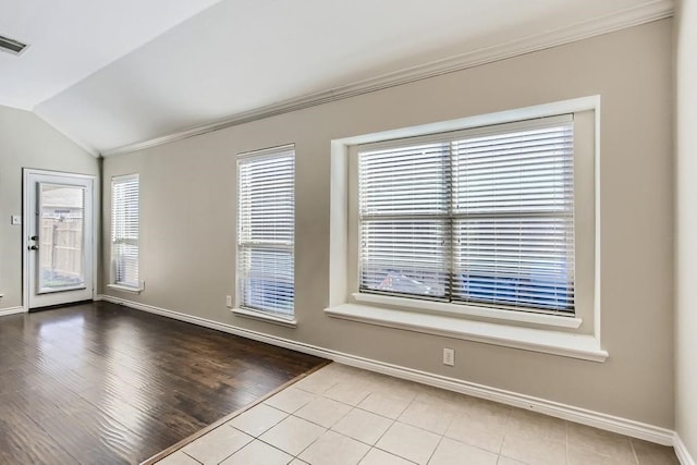 spare room with wood finished floors, baseboards, ornamental molding, and vaulted ceiling