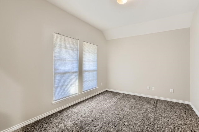 unfurnished room featuring lofted ceiling, baseboards, and dark colored carpet