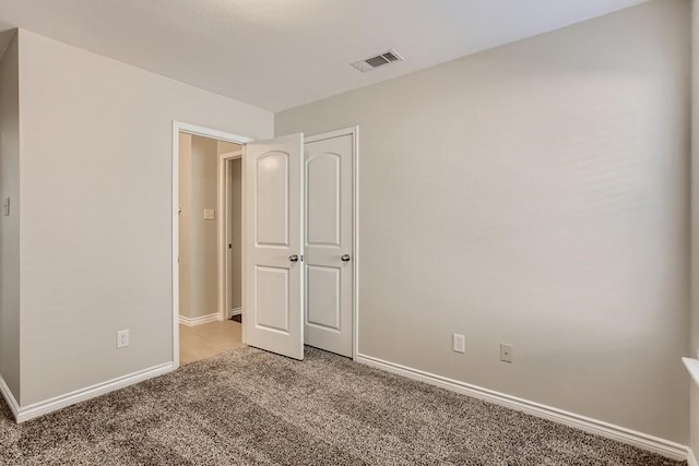 unfurnished bedroom featuring baseboards, visible vents, and light carpet