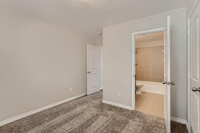 unfurnished bedroom with ensuite bathroom, baseboards, and carpet floors