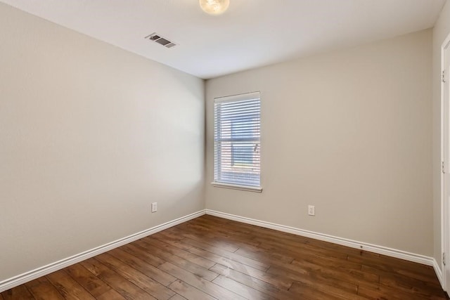 unfurnished room with baseboards, visible vents, and dark wood-style flooring