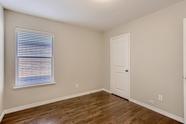 unfurnished room with dark wood-type flooring and baseboards