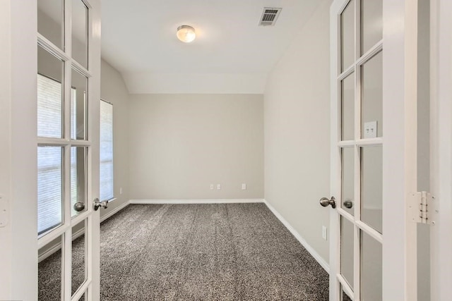 carpeted empty room with visible vents, french doors, baseboards, and vaulted ceiling