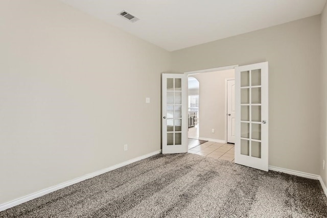 spare room with visible vents, baseboards, light carpet, light tile patterned floors, and french doors