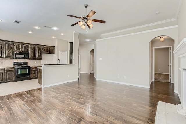 unfurnished living room with baseboards, visible vents, arched walkways, ornamental molding, and light wood-type flooring