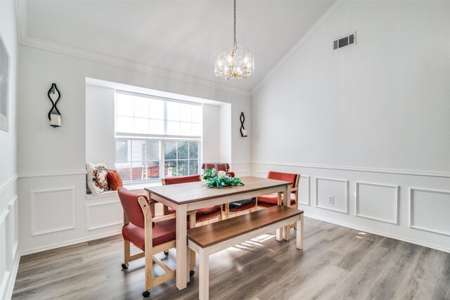 dining space featuring wood finished floors, visible vents, lofted ceiling, crown molding, and a notable chandelier