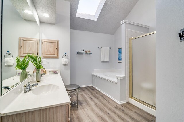 full bath with a shower stall, a skylight, wood finished floors, a bath, and a sink