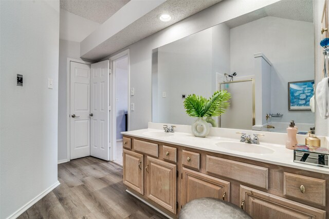 bathroom with double vanity, vaulted ceiling, wood finished floors, and a sink