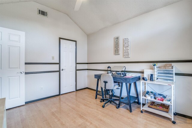 office featuring visible vents, a textured ceiling, lofted ceiling, and wood finished floors