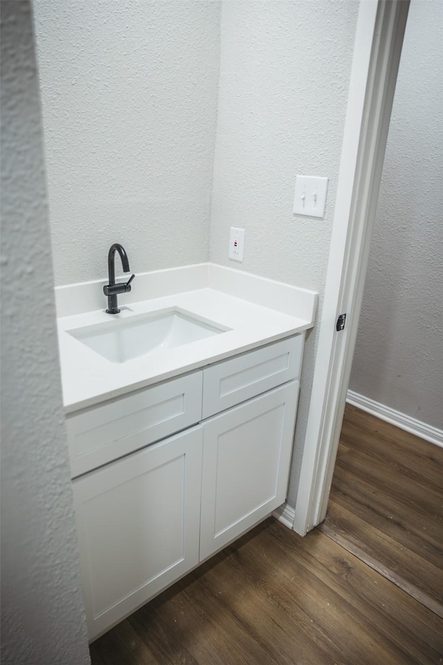 bathroom featuring vanity, a textured wall, and wood finished floors