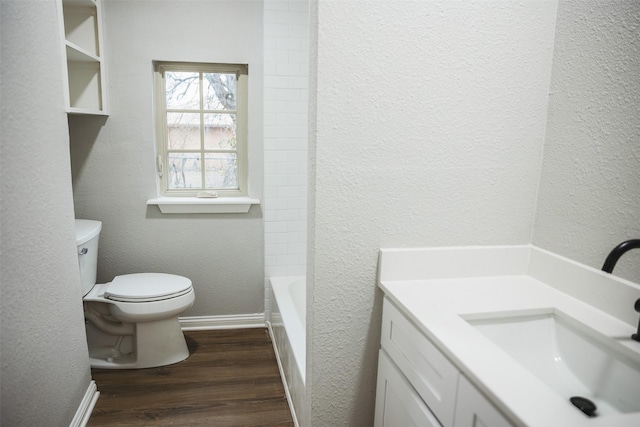 bathroom featuring vanity, wood finished floors, baseboards, toilet, and a textured wall