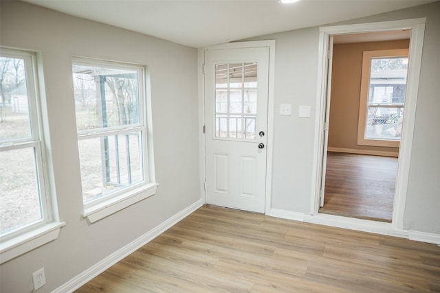 entryway featuring vaulted ceiling, light wood-style flooring, and baseboards