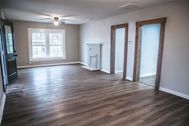 unfurnished living room with visible vents, a ceiling fan, dark wood finished floors, a fireplace, and baseboards