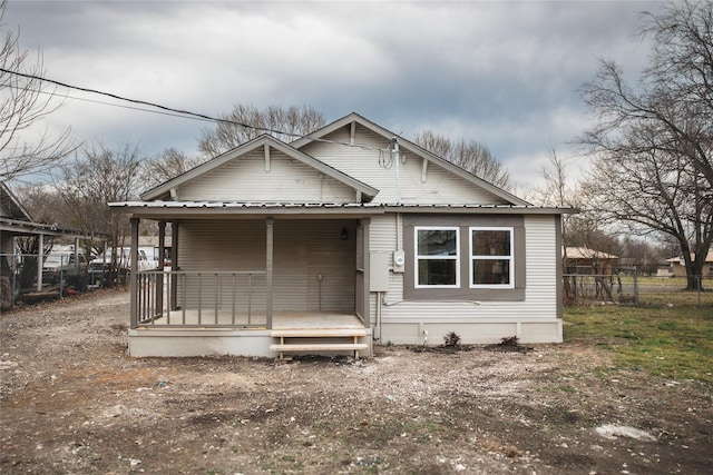 bungalow-style home with fence, covered porch, and metal roof