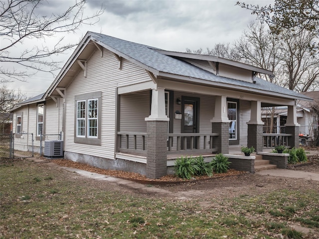 view of front of property with fence, covered porch, central AC, and roof with shingles