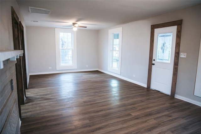 unfurnished living room featuring dark wood finished floors, visible vents, a fireplace, and baseboards