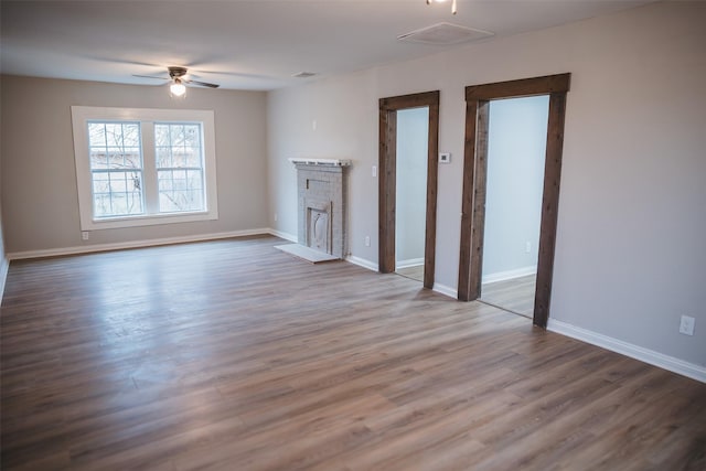 unfurnished living room featuring baseboards, a ceiling fan, wood finished floors, and a fireplace