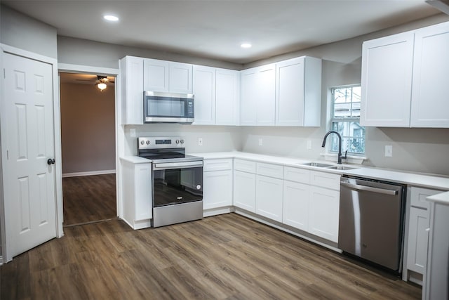 kitchen with dark wood-style floors, a sink, stainless steel appliances, light countertops, and white cabinets