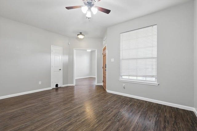 empty room featuring dark wood finished floors, a ceiling fan, and baseboards