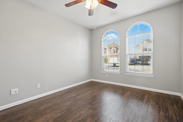 spare room with ceiling fan, baseboards, and dark wood-style floors