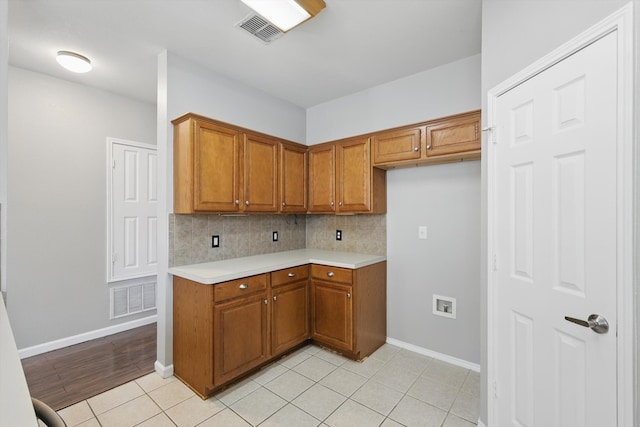 kitchen featuring visible vents, brown cabinets, backsplash, and light countertops