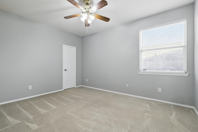 empty room with carpet flooring, a ceiling fan, and baseboards