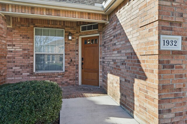 entrance to property with brick siding and roof with shingles