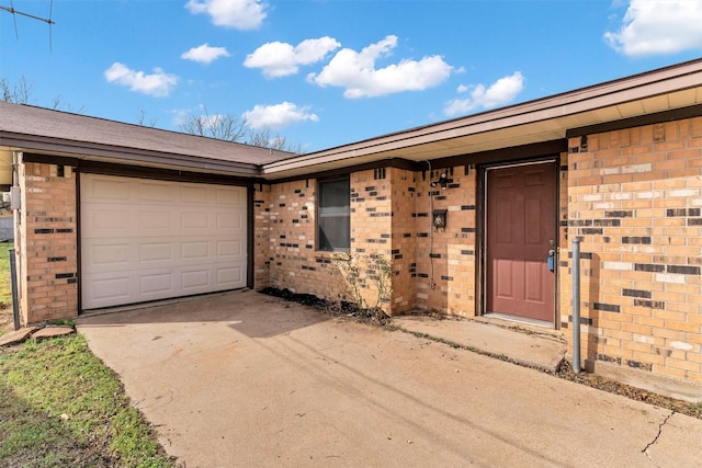 doorway to property with concrete driveway, a garage, and brick siding